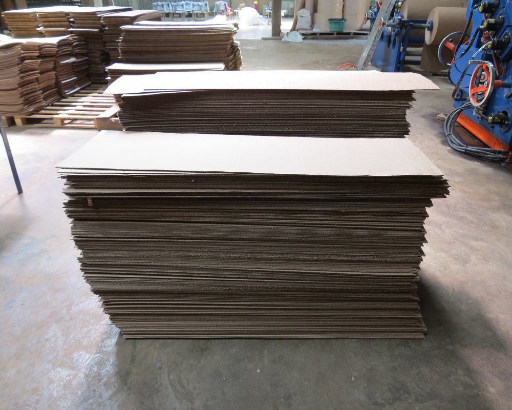 Board sheets stacked at an unrelated corrugated-box plant; not KKPK’s warehouse or actual available stock
