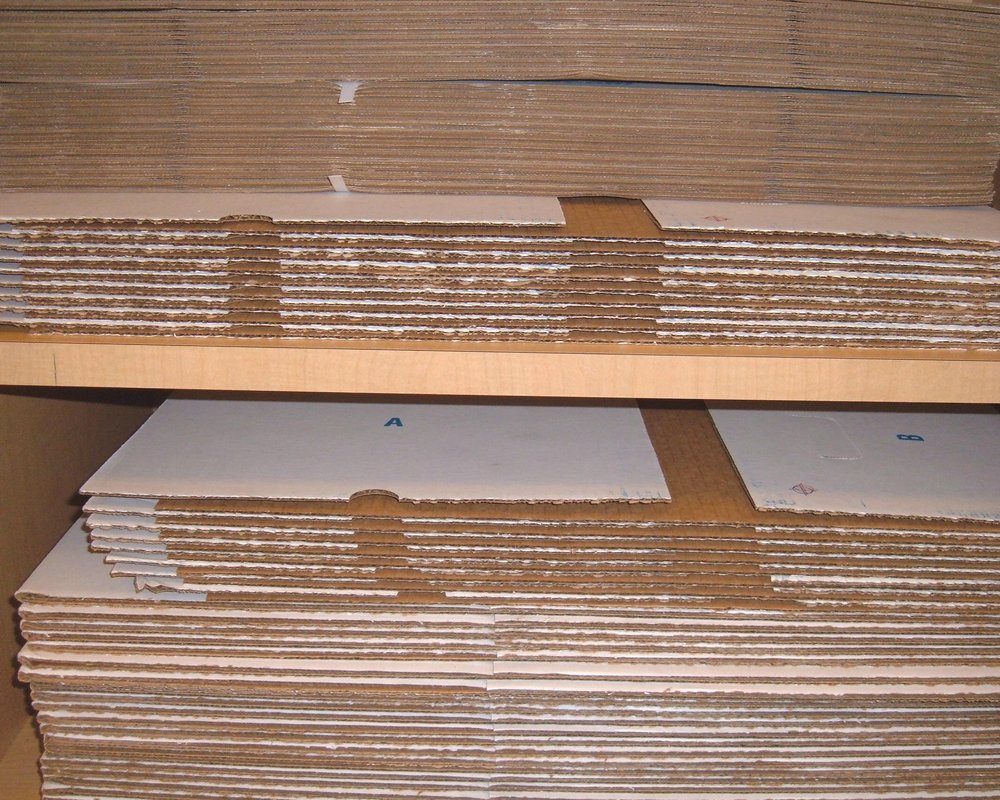 Flat unassembled corrugated banker&rsquo;s boxes on a shelf; not returned or tested shipping cartons